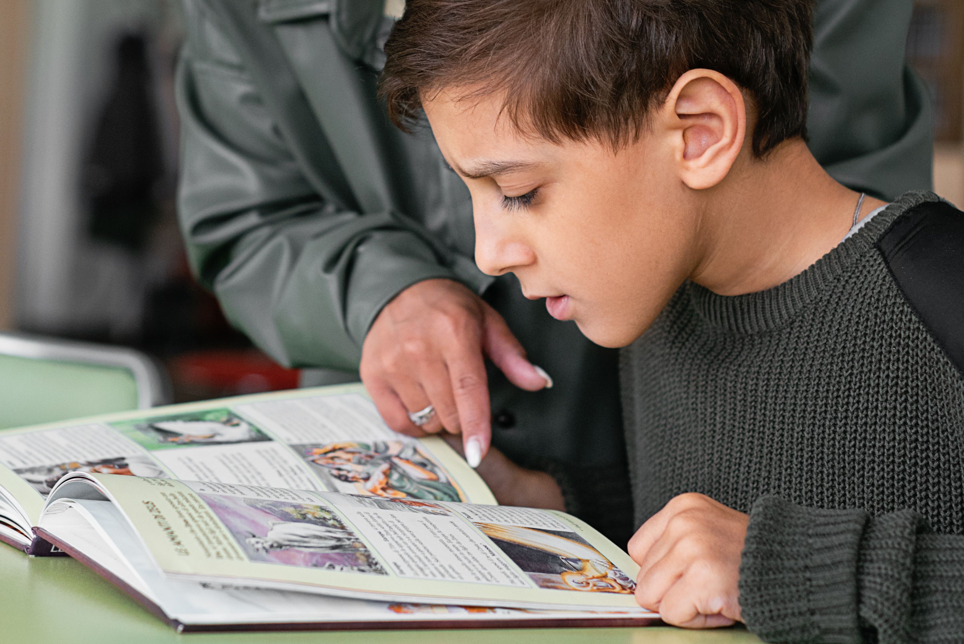 Tutor pointing at a book while a child reads intently
